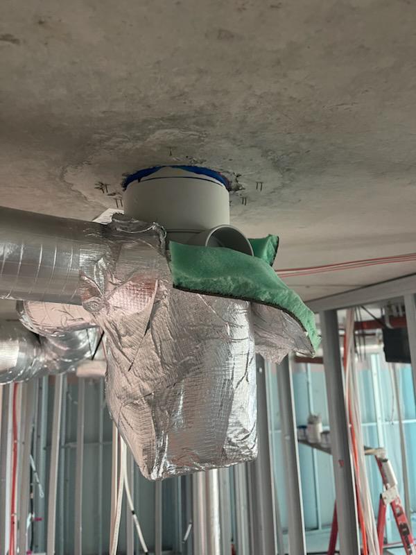 Cast-in fire collar partly obscured by concrete slurry and surrounding construction residue after the concrete pour