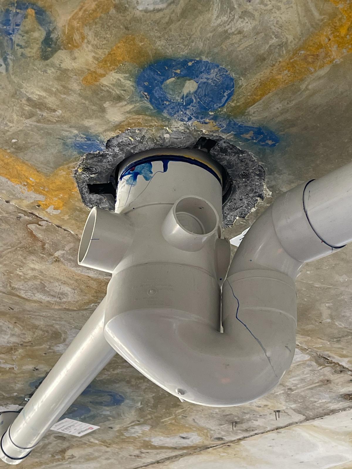 Damaged existing cast-in fire collar around a PVC-U penetration below a concrete slab
