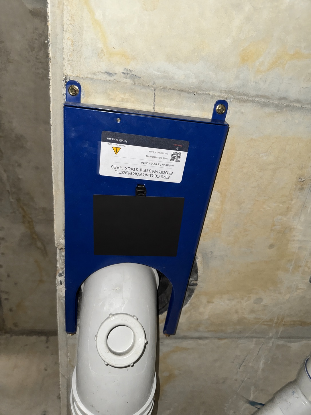 Fendix fire collar installed around a PVC-U pipe beside a concrete edge beneath an existing Cougar cast-in collar