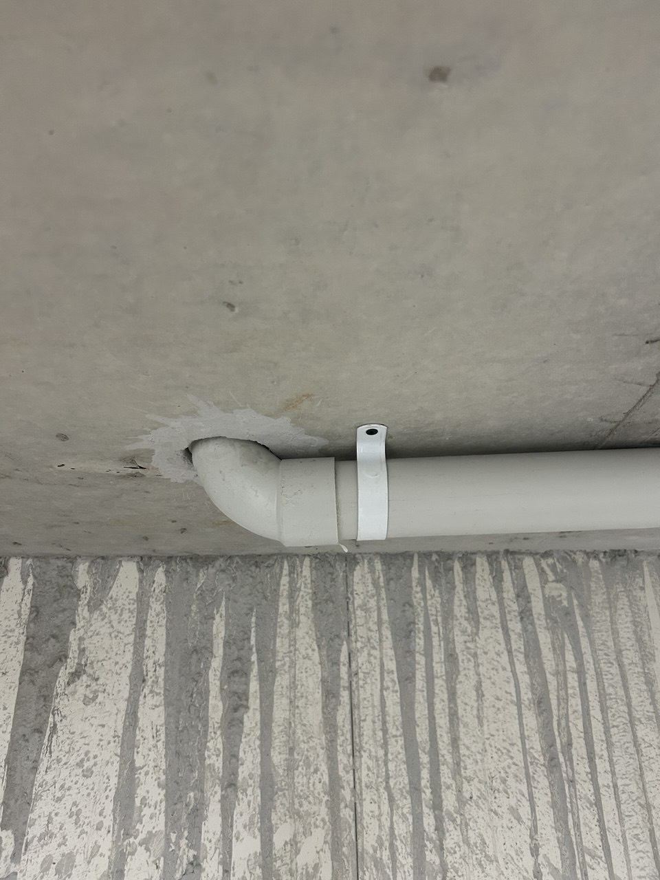 PVC pipe elbow turning directly beneath a concrete slab before a fire collar is fitted